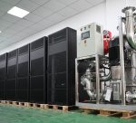 Whatsminer Hydro Cooling Cabinet (2 numbers), showcasing a row of tall black server cabinets designed for cryptocurrency mining operations, with a large metallic cooling system equipped with pipes and pumps to the right, all placed on wooden pallets in an industrial setting